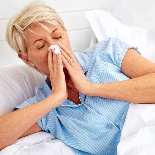 Blowing nose, couple or sick old woman in bed with husband with flu virus, cold or health problem. Sneeze, mature or senior pers